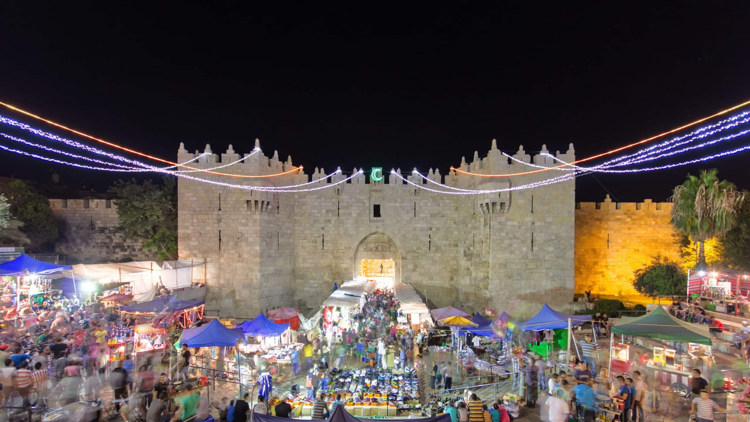 שער שכם בלילה עם אורות צבעוניים ושווקים הומים