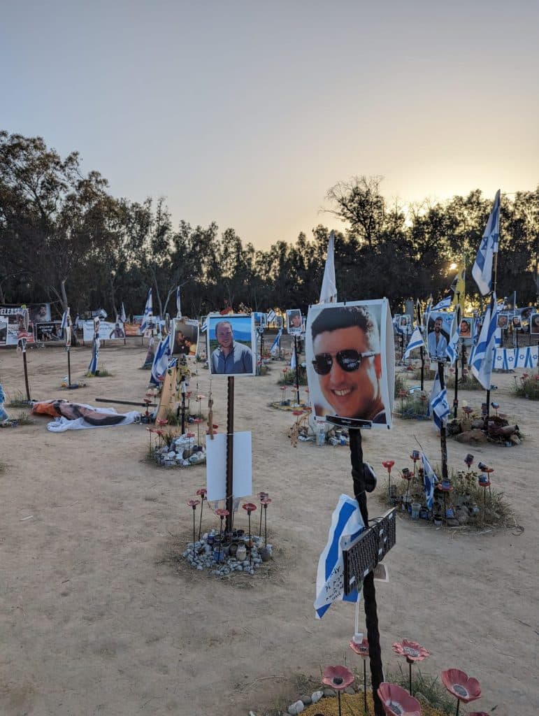 עמודים עם פרחים, דגלים ותמונות ההרוגים והחטופים מהמסיבה ברעים