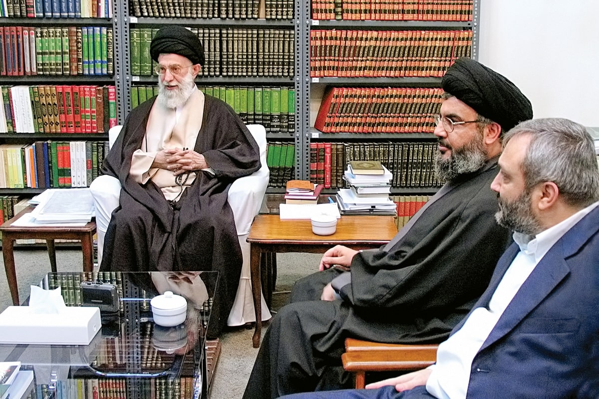 Khamenei with Nassralla meeting, a bookcase full of books in the background