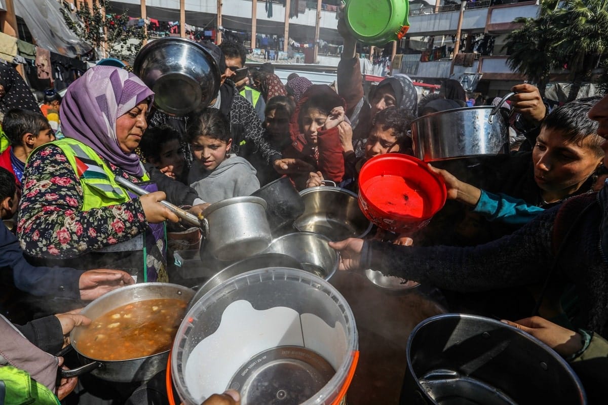 women and children collect food with pots